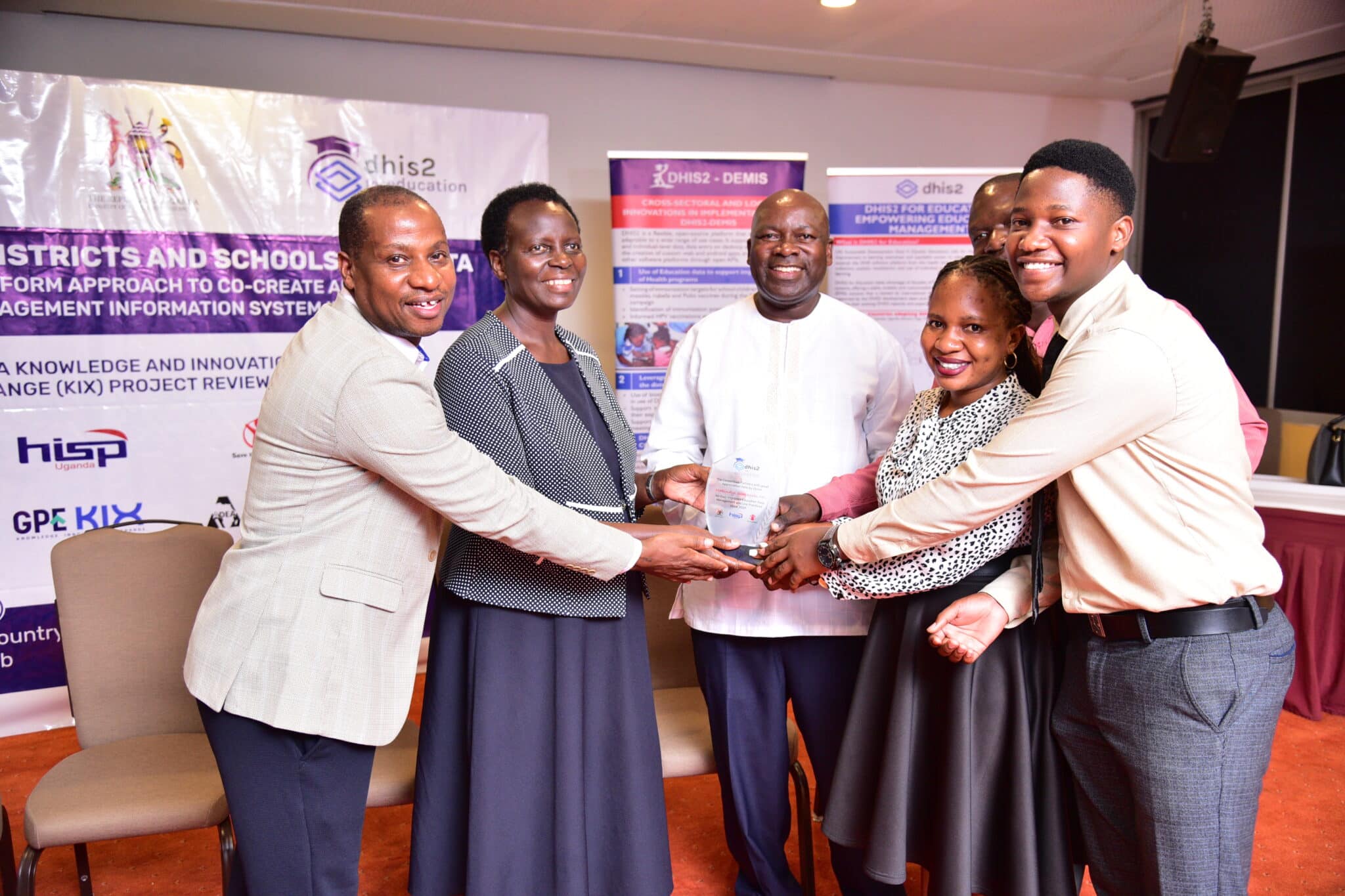 From left, HISP Uganda director of programs Dr. Prosper Behumbiize, Ministry of Education and Sports Permanent Secretary Dr. Kedrace Turyagyenda, and Commissioner of the Basic Education Department Dr. Cleophus Mugenyi, present an award to three representatives of the Education Department of Makindye Sabagabo Municipal Council. (Photo by Joseph Nkoola)